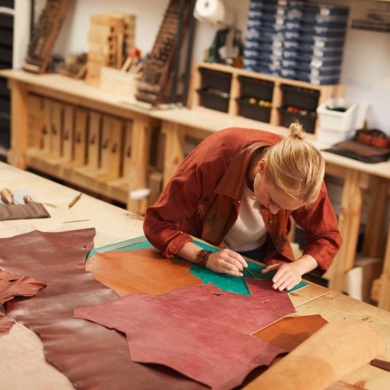 Artisan coupant du cuir de qualité pour réaliser un tablier dans un Atelier